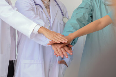 Doctors and nurses stacking their hands together in a group.